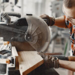 Wood cutting with circular saw. Closeup of mature man sawing lumber.